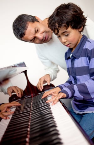 Boy taking piano lessons at home with a tutor