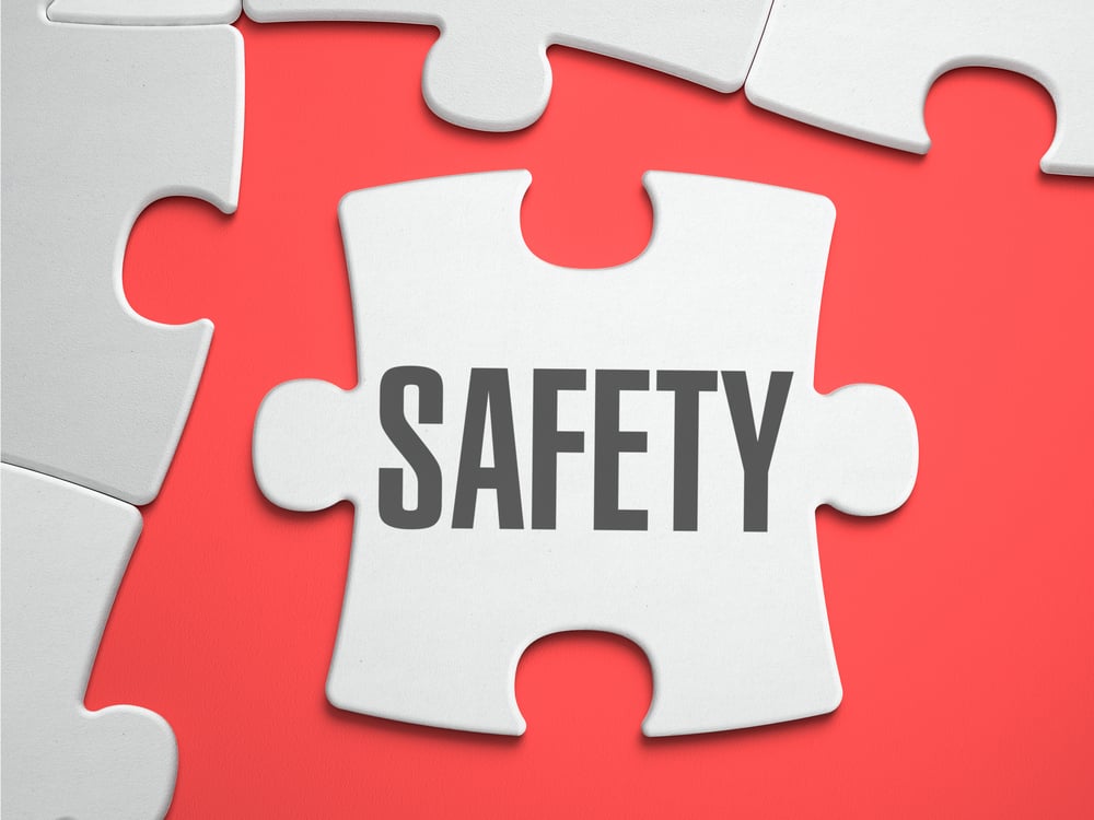 Safety - Text on Puzzle on the Place of Missing Pieces. Scarlett Background. Close-up. 3d Illustration.